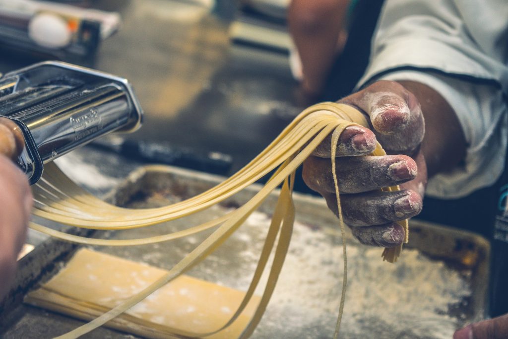 Close-up of hands making fresh pasta, showcasing artisanal techniques and ingredients.